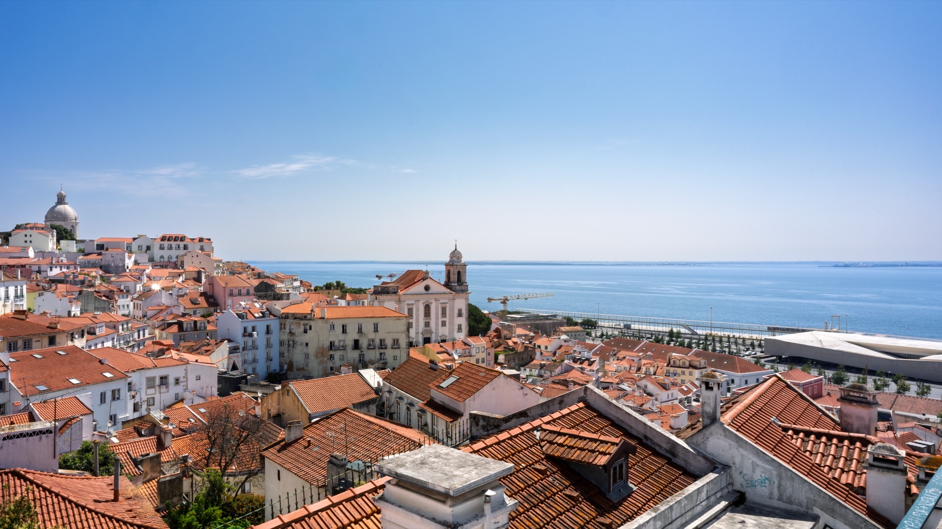 Panoramic view over Lisbon tile rooftops, Alfama, and the Tagus River